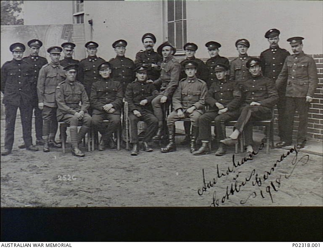 Cottbus, Germany. c. 1918. Formal group portrait of Australian prisoners of war (POW). The men are wearing a mixture of Australian Army uniform and a darker uniform and peaked hats issued by the Germans. They have been permitted to continue wearing their rank stripes, rising sun badges and awards. Australian War Memorial collection P02318.001